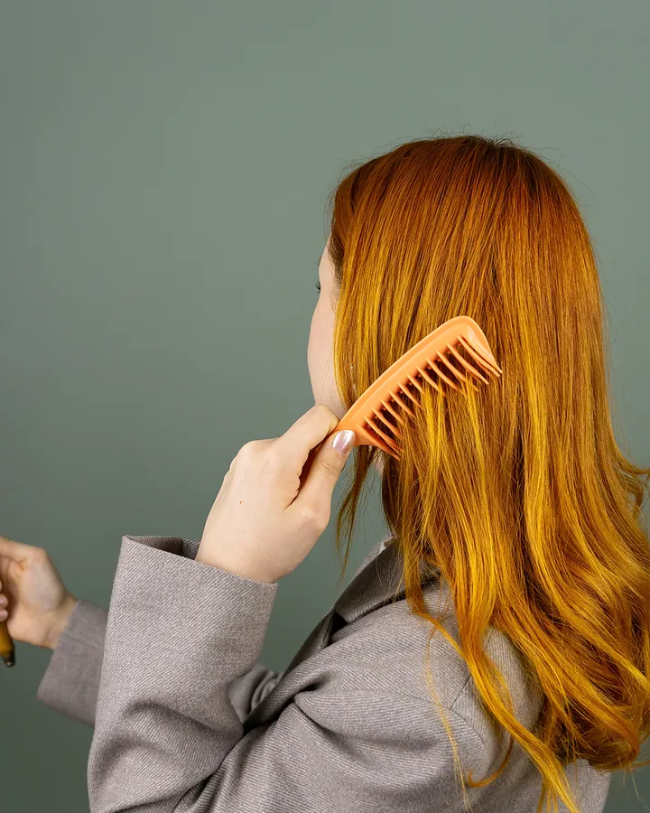 Cabelo comprido acobreado, liso e brilhante, a ser penteado com um pente largo.