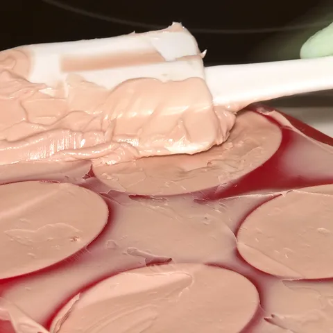 Discos de creme rosado espalhados com uma espátula.