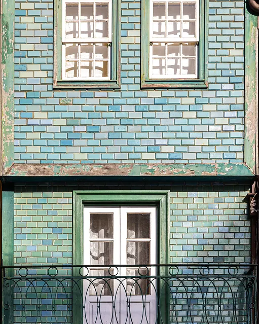 Fachada revestida de azulejo azul, com janelas e varanda de ferro, fotografia provisória.