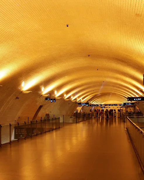 Corredor abobadado de uma estação de metro, com luz amarela ao fundo, fotografia provisória.