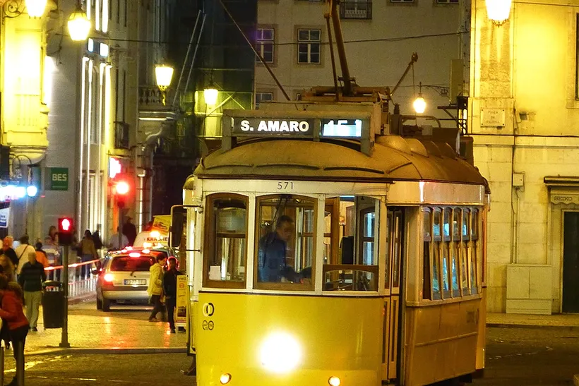 Elétrico amarelo numa rua da cidade à noite, fotografia provisória.