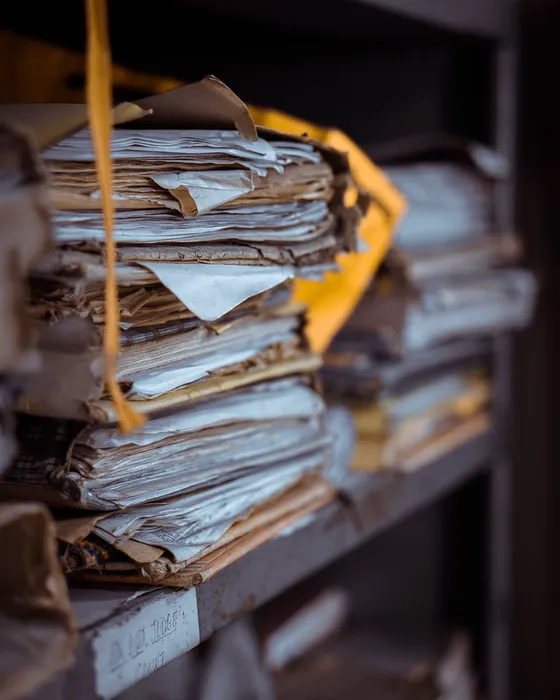 Prateleiras com pastas e maços de documentos atados.