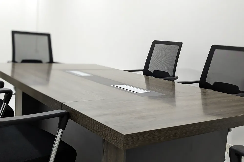 Sala de reuniões vazia com uma mesa comprida e cadeiras alinhadas.