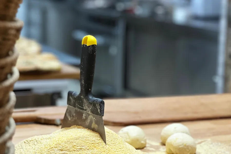 Bolas de massa já divididas na bancada enfarinhada, com uma espátula