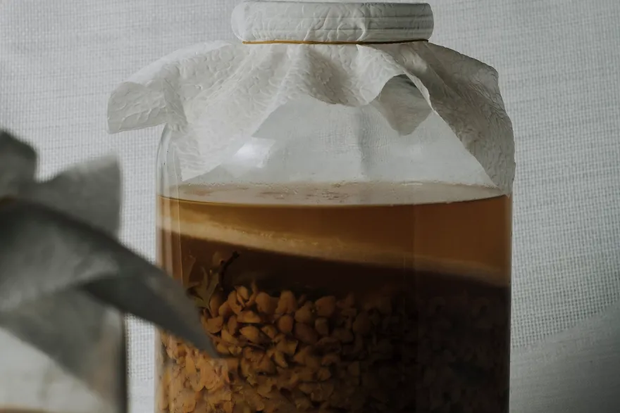 Frasco de fermento natural, tapado com papel, na bancada