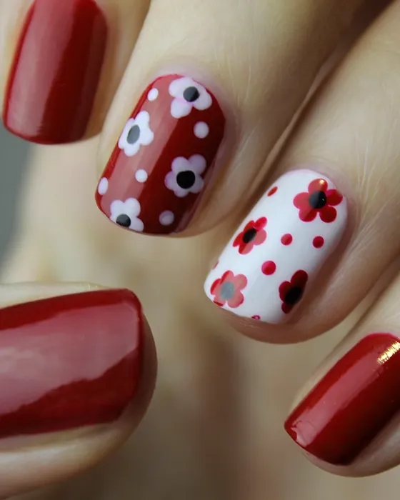 Nail art de flores brancas e vermelhas sobre fundo vermelho e branco.