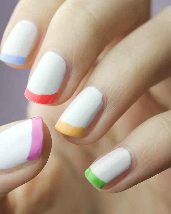 Francesa colorida: unhas brancas com a ponta em rosa, laranja, verde e azul.